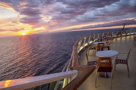 Sunset on a cruise ship with tables and chairs. Carefully shot scene making sure that no copyrighted ship design is depicted.